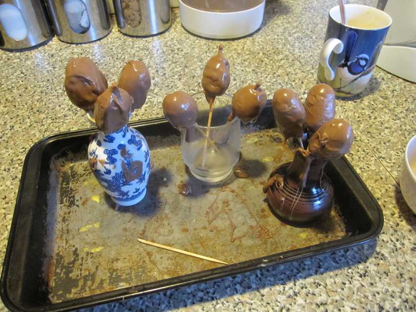 tray of small vases each holding several dripping chocolate eggs on skewers