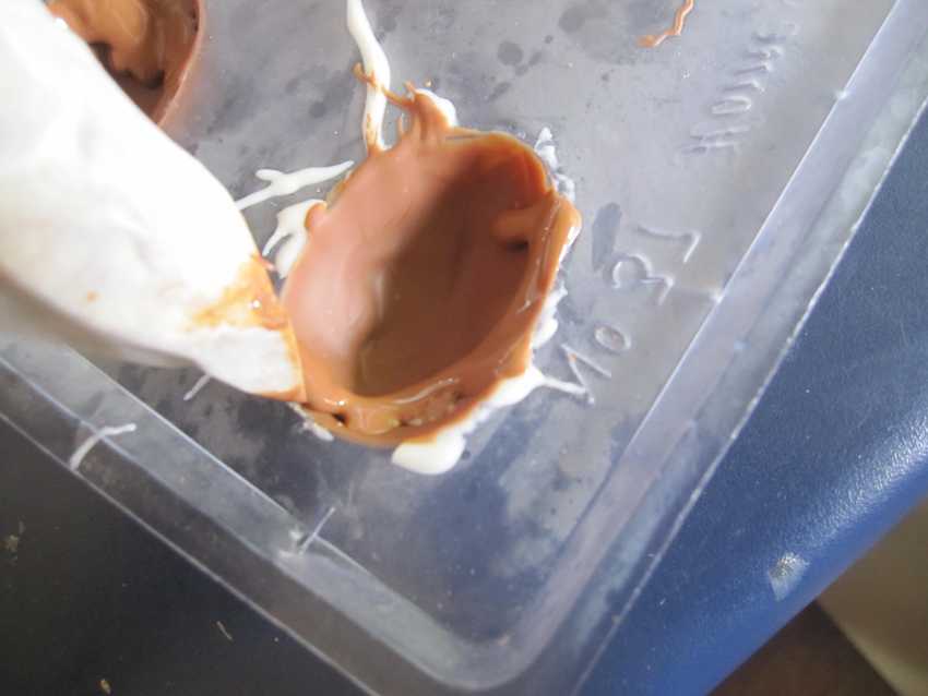 piping bag being used to thicken rim of chocolate shells in the mould tray