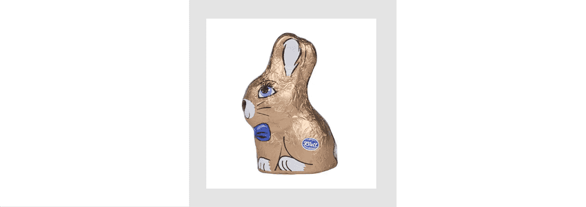 Gold‑foil‑wrapped chocolate bunny with printed blue eyes, a blue bow tie, and white and black facial and paw details, featuring a blue oval label.