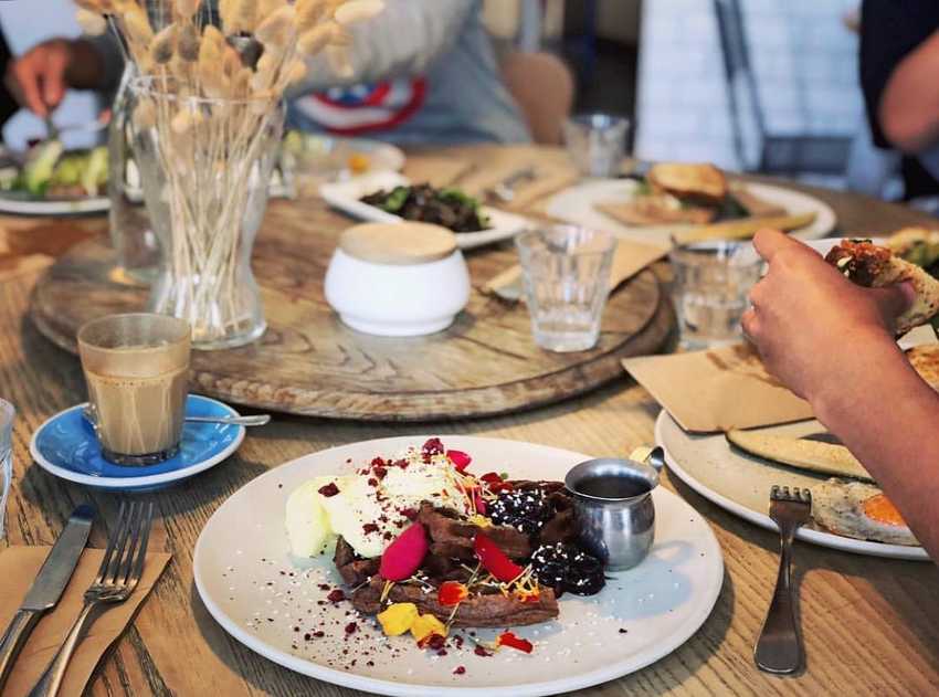 Cafe table with delicious-looking tart in front focus