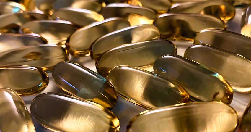 Pile of Omega 3 capsules on a grey surface