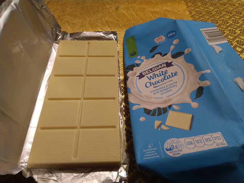 opened block of white chocolate.  It is wrapped in silver paper and has the paper wrapper on the side.