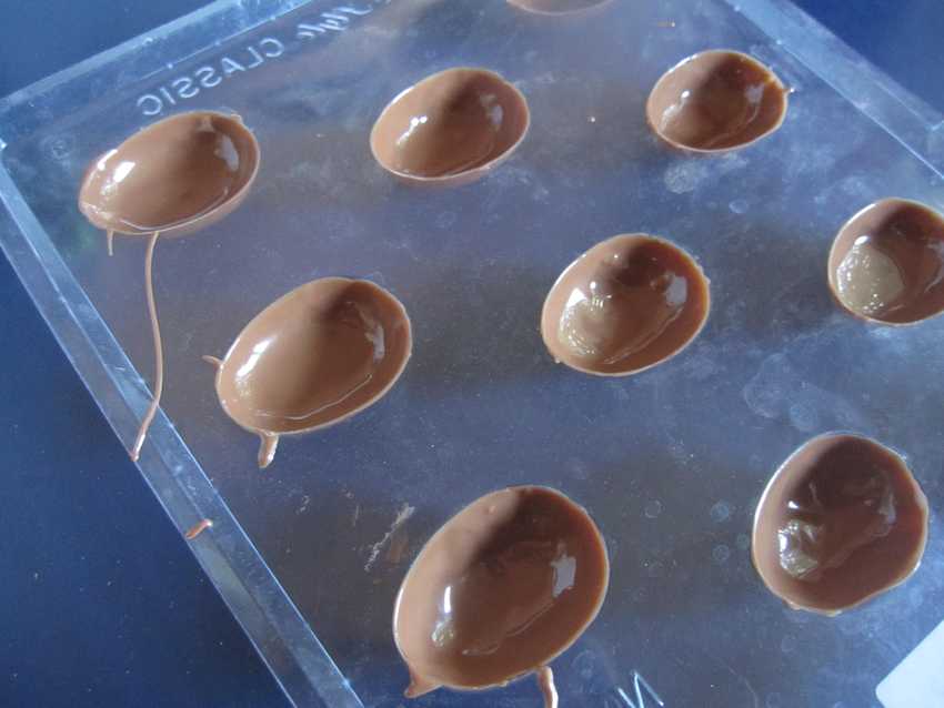chocolate mould tray with thin coat in each egg-shaped depression