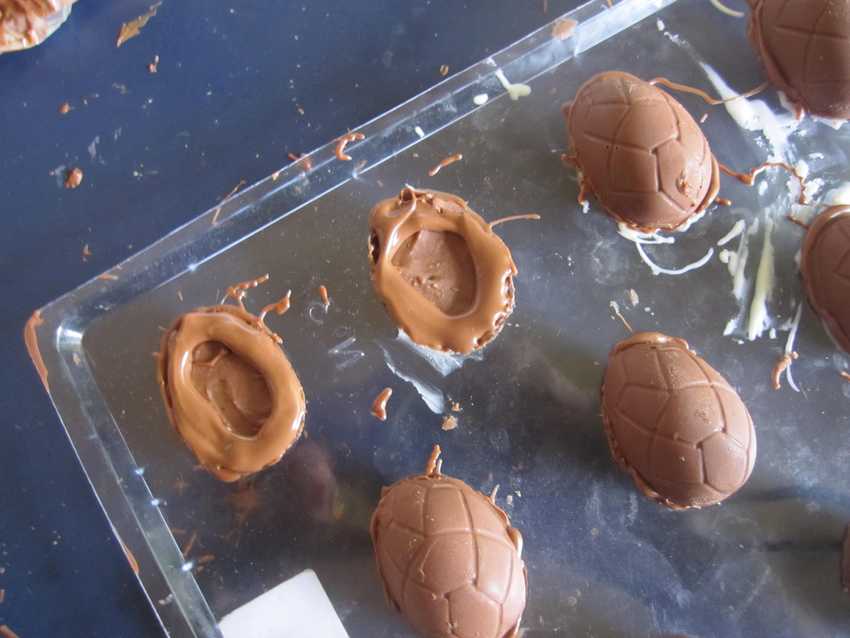 tray of chocolate moulds with filling inside and additional layer of chocolate on top of the filling around the edge