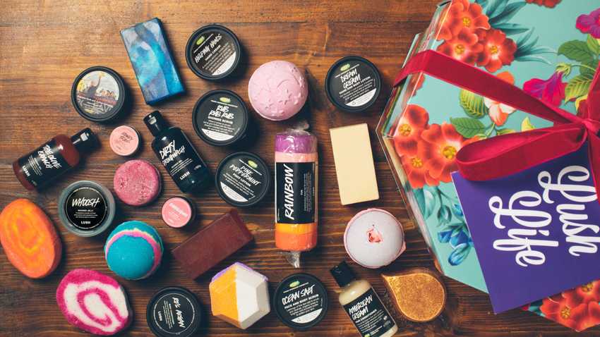 a selection of LUSH products scattered over a wooden table