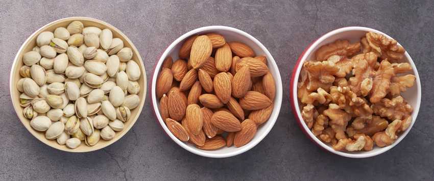 bowls of pistachios, almonds and walnuts